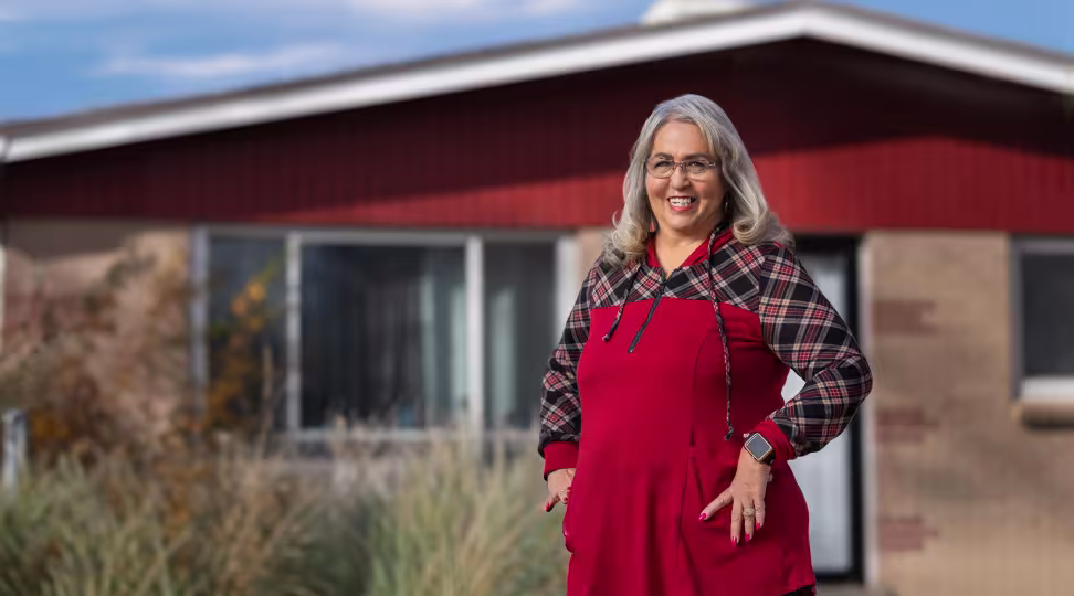 A woman in a red dress in front of a house smiling