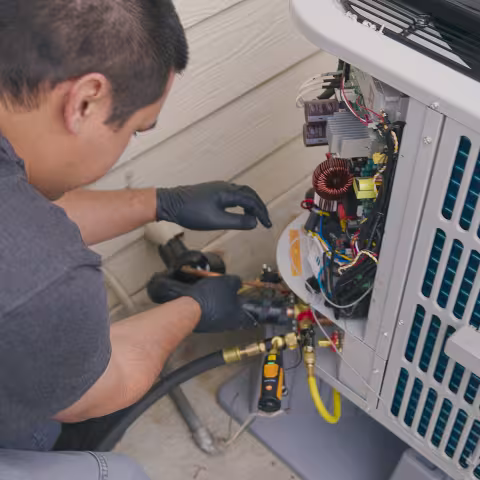An HVAC repairman inspecting a heating and cooling setup