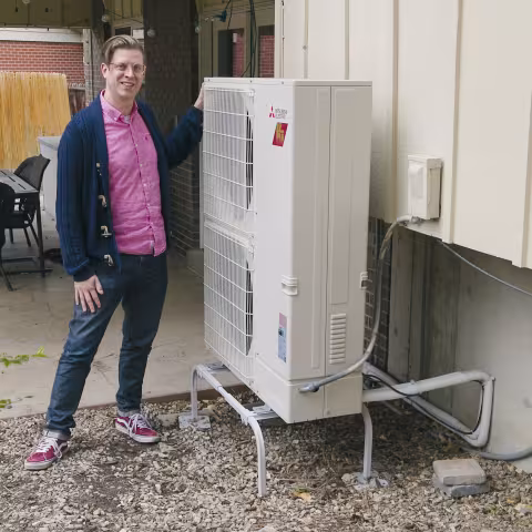 A man standing next to a heat pump